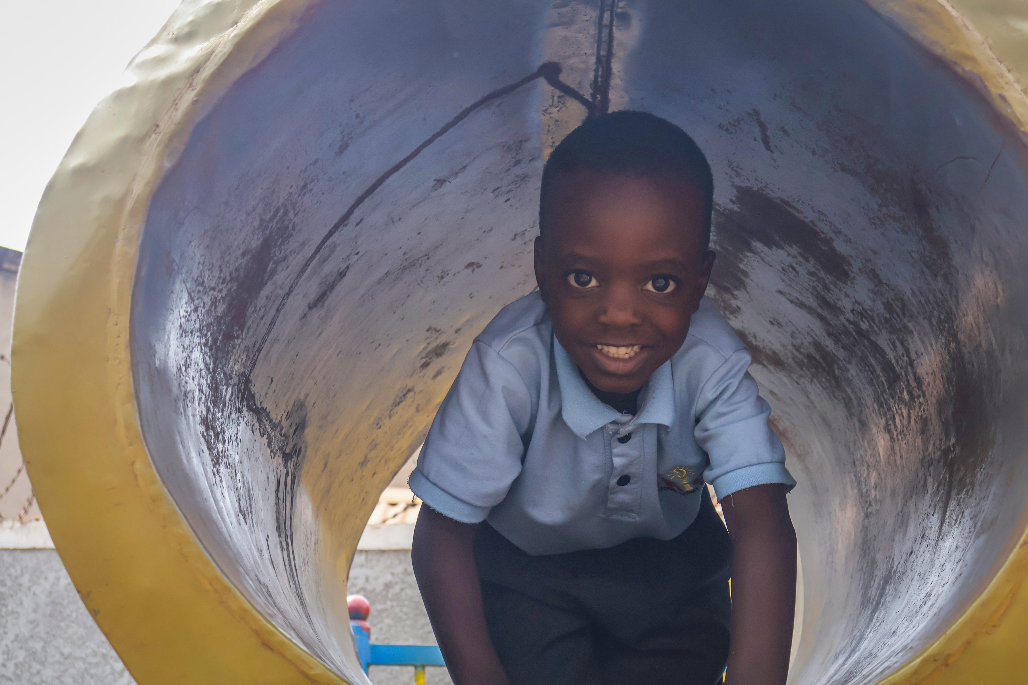 Student grinning inside the playground tunnel slide